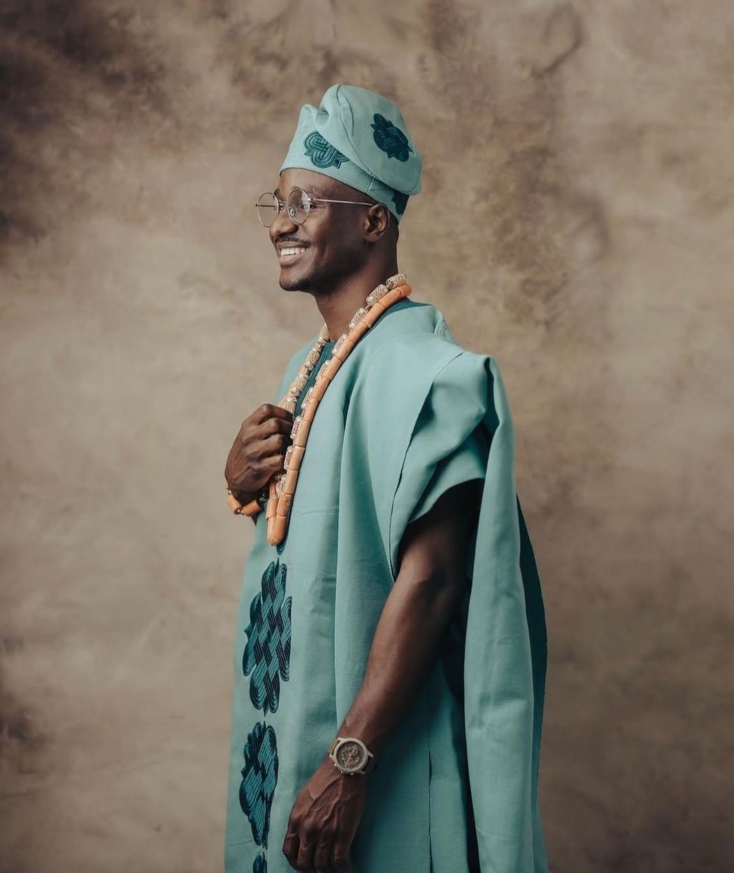 Groom in a sage agbada with tonal embroidery, side profile